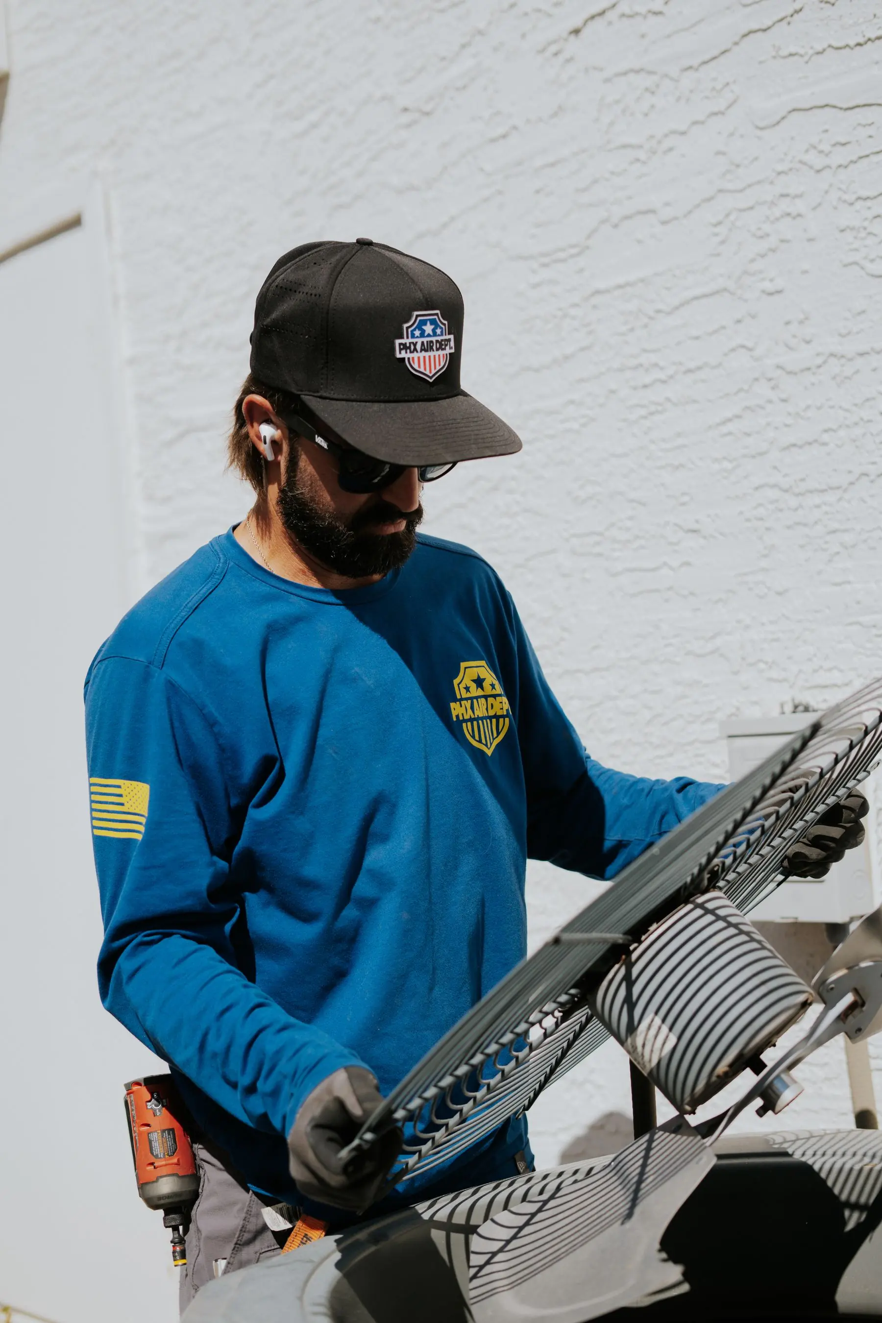 Technician repairing an AC condenser fan grille